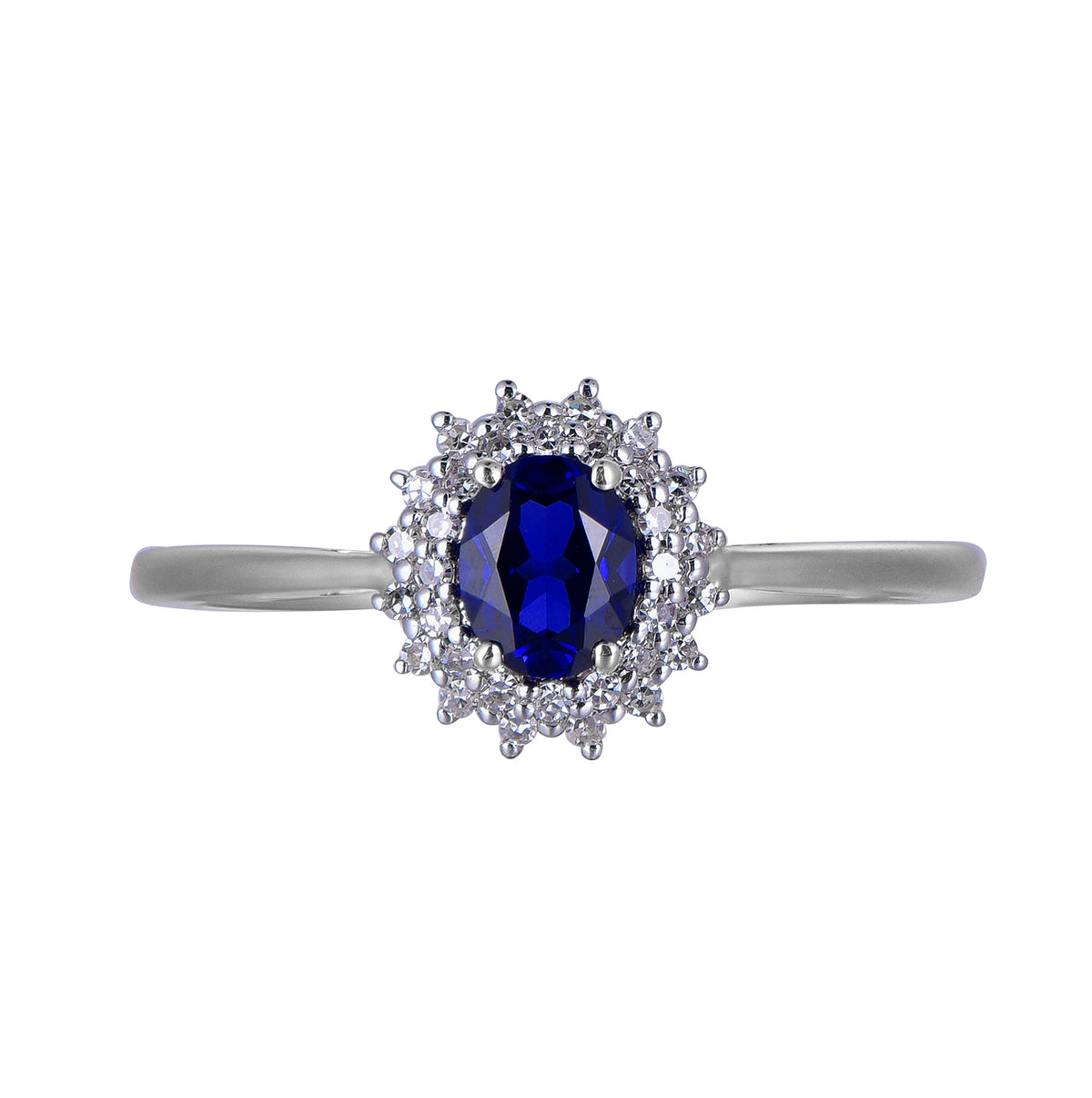 A white gold ring featuring an oval-cut deep blue sapphire center stone surrounded by a halo of small clear stones, set on a plain white background.